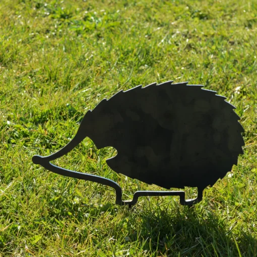 Pindsvin i bevægelse – metalfigur i cortenstål stående i solen i en grøn have.